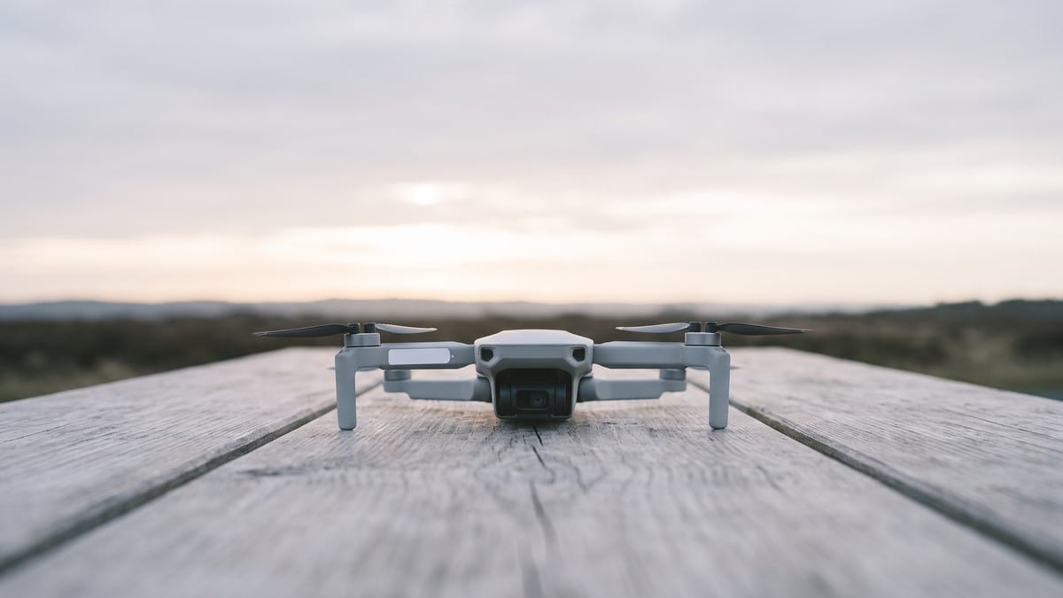 Un piccolo drone al centro di un tavolo all'aperto all'alba, con una piccola etichetta bianca applicata sulla fiancata